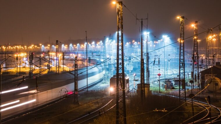 Industrianläggning med kraftledningar och rök mot kvällshimlen